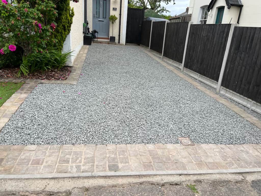 A resin-bound gravel driveway with block-paved edging and a new fence line down one side.